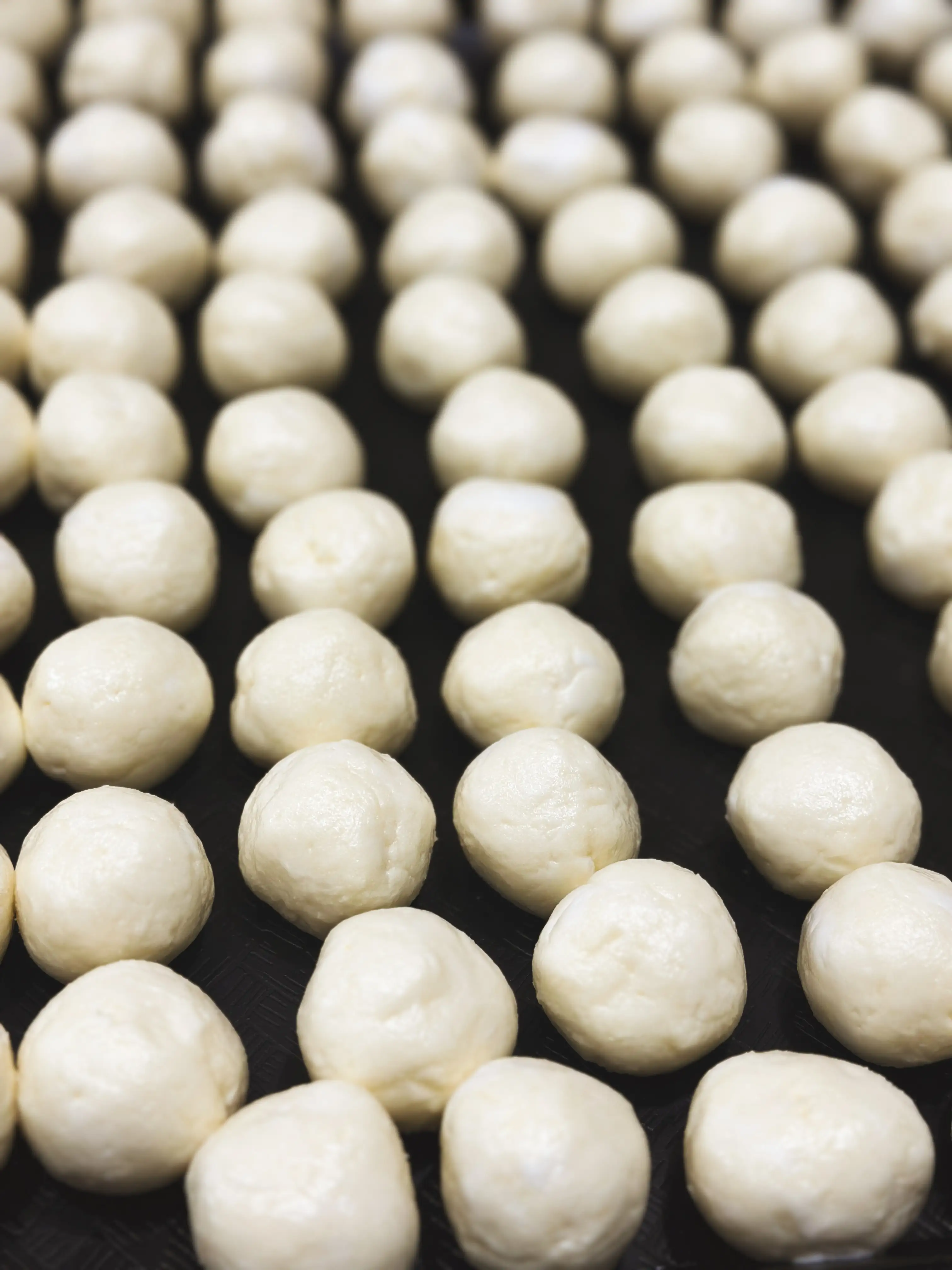 Small cheese bread dough balls arranged on a baking tray